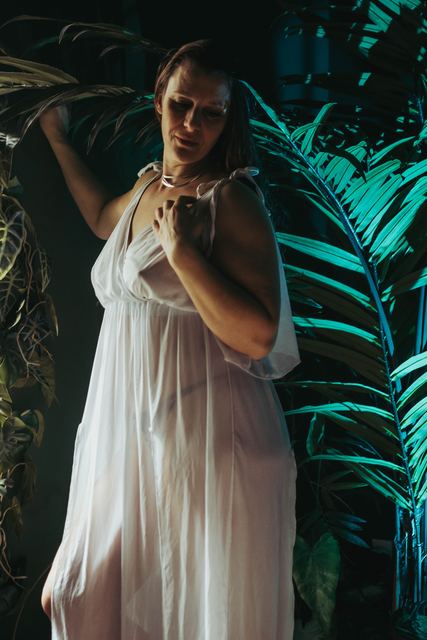 Femme en robe blanche vaporeuse entourée de feuillages
